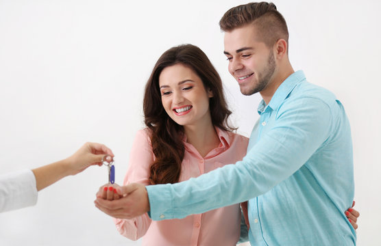 Hands of estate agent giving keys to  couple, on light background