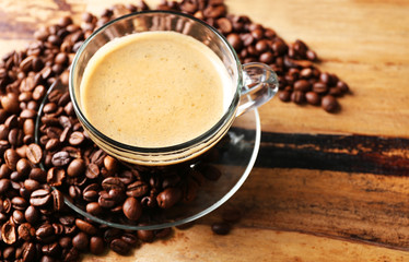 Cup of coffee and coffee grains on wooden table background
