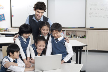 Students and teacher gathered around a computer in the classroom