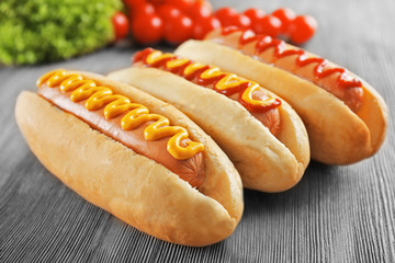 Tasty hot-dogs with vegetables on wooden background