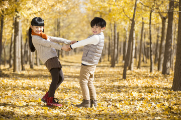 Two children playing in autumn woods