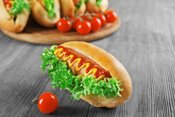 Tasty hot-dog with tomatoes on wooden table