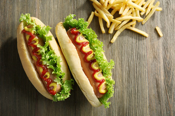 Tasty hot-dogs with French fries on wooden background