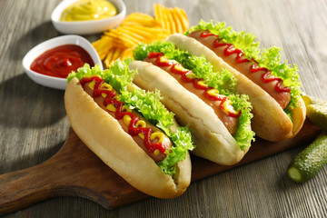 Tasty hot-dogs with chips and pickled cucumbers on wooden background