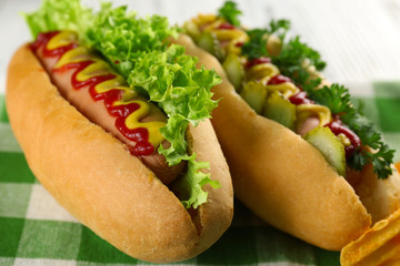 Delicious hot-dogs with chips on green checkered cotton napkin, close up