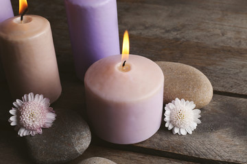 Fototapeta na wymiar Spa set with candles, pebbles and flowers on wooden background, close up