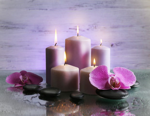 Spa composition with candles, pebbles and flowers on grey  background