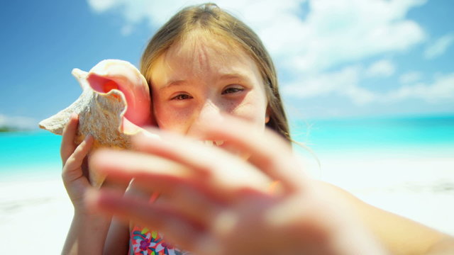 Portrait of a little Caucasian girl on a vacation beach with a conch shell