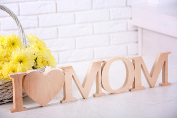 Fototapeta na wymiar Wooden decor and flowers for mother's day on brick wall background