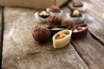 Different tasty chocolate candies on wooden table, close up