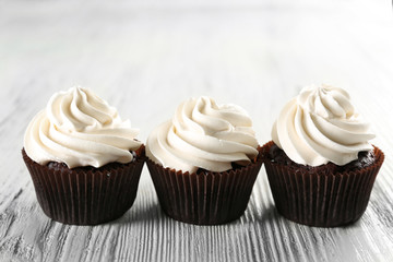 Tasty cupcakes on white wooden background, close up