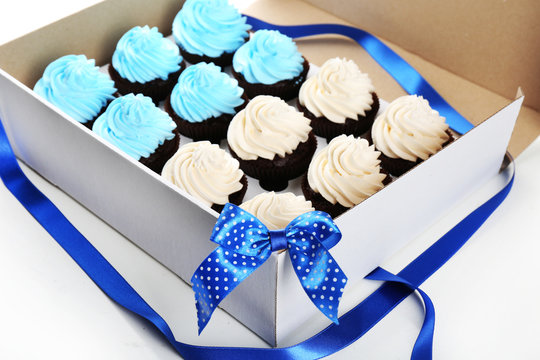 Tasty cupcakes in paper box decorated with ribbon and bow, close up