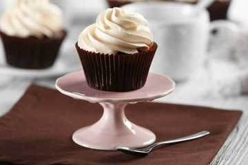 Delicious chocolate cupcake with cream on served table, close up