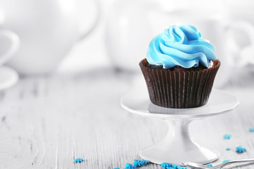 Delicious chocolate cupcake with blue cream on served table, close up