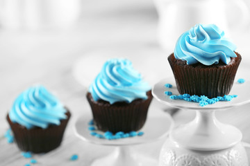 Delicious chocolate cupcakes with blue cream in a row on decorated wooden  table, close up
