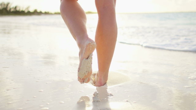 Legs of a Caucasian female walking barefoot on a beach 