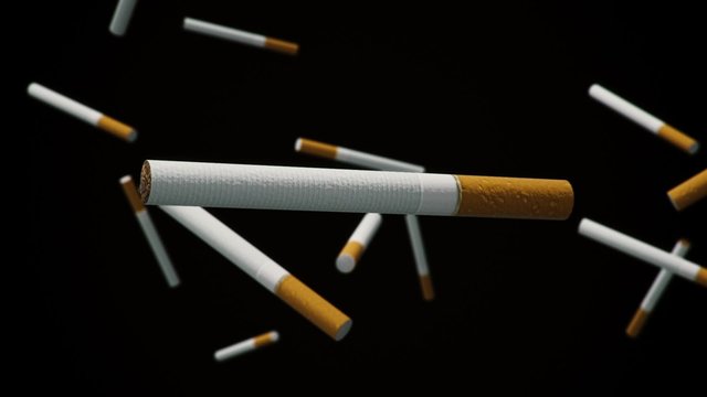 Cigarette floating in space against a black background with a shallow depth of field.