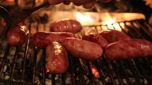 thick sausages are cooked on the grill of the fireplace with a lighted fire