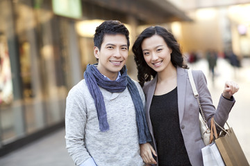 Fashionable young couple with shopping bags in city street