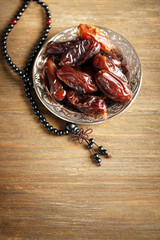 Dates fruit and rosary on wooden background, close up