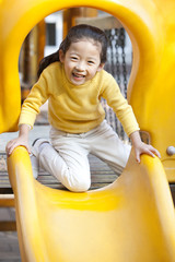 Fototapeta na wymiar Girl playing on playground slide