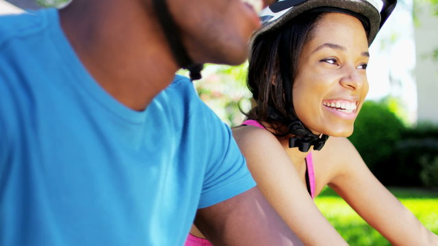 Young active African American couple cycling to keep fit outdoors