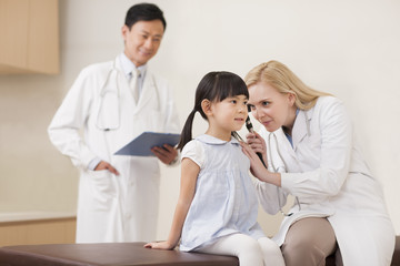 Doctor examining girl's ears