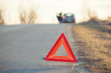 Red warning triangle on a road with a failure car