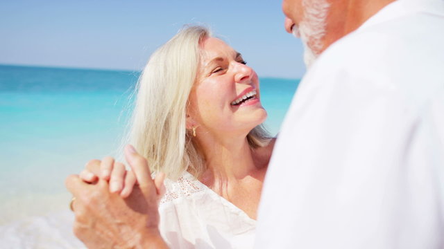 Happy retired couple dancing together on a tropical beach