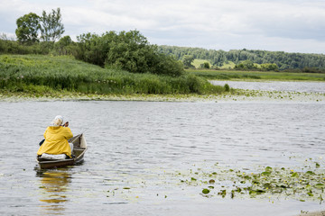 In summer, the woman fisherwoman boat floats on the river with a