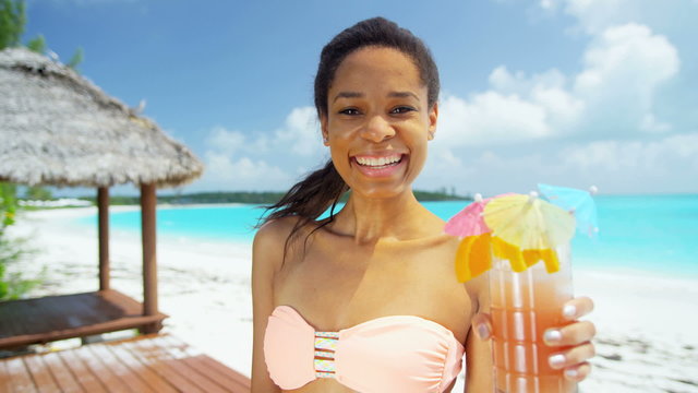 Happy young African American girl enjoying party cocktail on beach