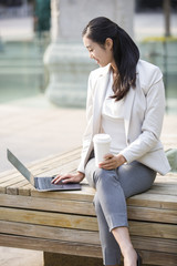 Young businesswoman working with laptop outdoors