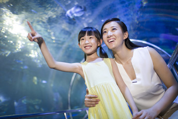 Young mother and daughter in aquarium