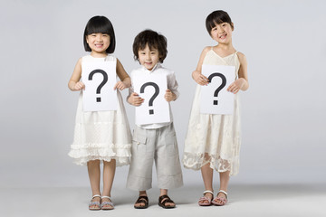 Children holding signs with question marks
