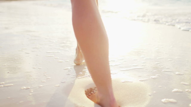 Legs of a female Caucasian barefoot on the ocean beach 
