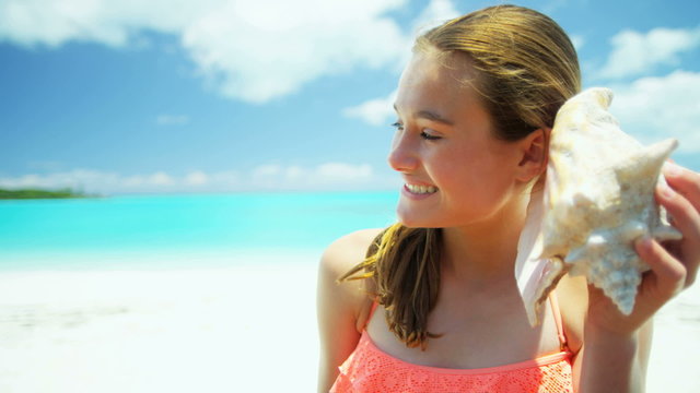Portrait of smiling Caucasian girl on a beach holding a conch shell