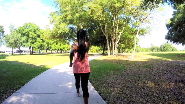 Young active African American fitness girl enjoying power walking in park