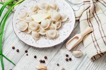 Russian national cuisine , cooked dumplings with meat, spices , green onions, pepper, salt and butter on a wooden background