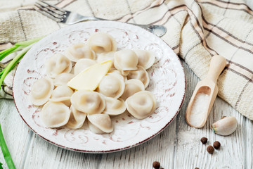 Russian national cuisine , cooked dumplings with meat, spices , green onions, pepper, salt and butter on a wooden background