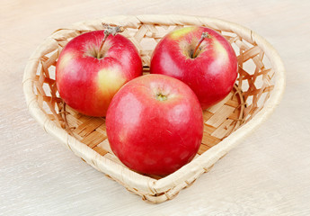 Wicker basket heart shaped with apples. Shot with limited depth of field. In the frame area of the blur. Artistic technique.