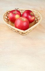 Wicker basket heart shaped with apples. Shot with limited depth of field. In the frame area of the blur. Artistic technique.