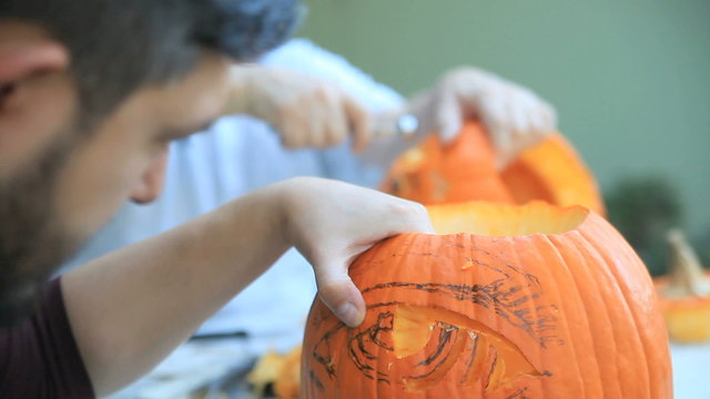 Two men carving Halloween pumpkins  