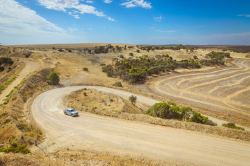 Car driving up hill on curvy rural dirt road