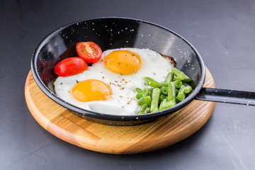 Fried egg on a pan served with tomato and asparagus