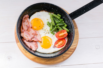 Fried egg on a pan served with tomato and asparagus