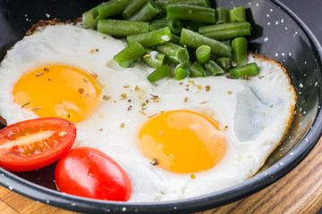 Fried egg on a pan served with tomato and asparagus