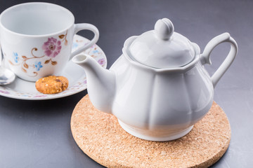 teapot and tea cup over dark background