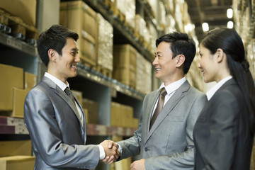 Business people shaking hands in warehouse