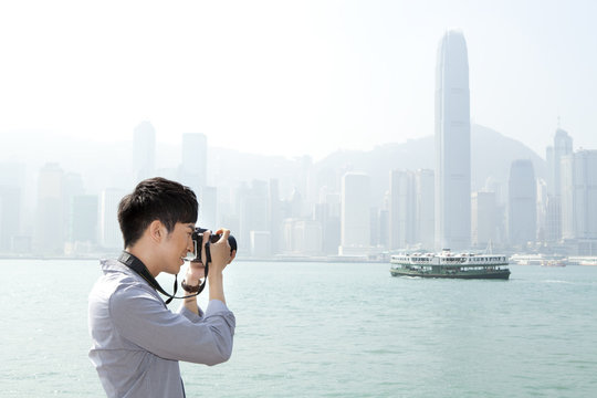 Young Man Photographing With SLR Camera In Victoria Harbor, Hong Kong