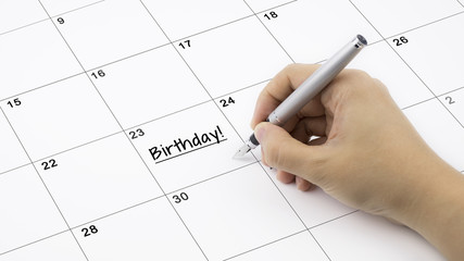 Concept image of calendar with a woman hand writing. Words Birthday written on calendar to remind you an important appoinment.
